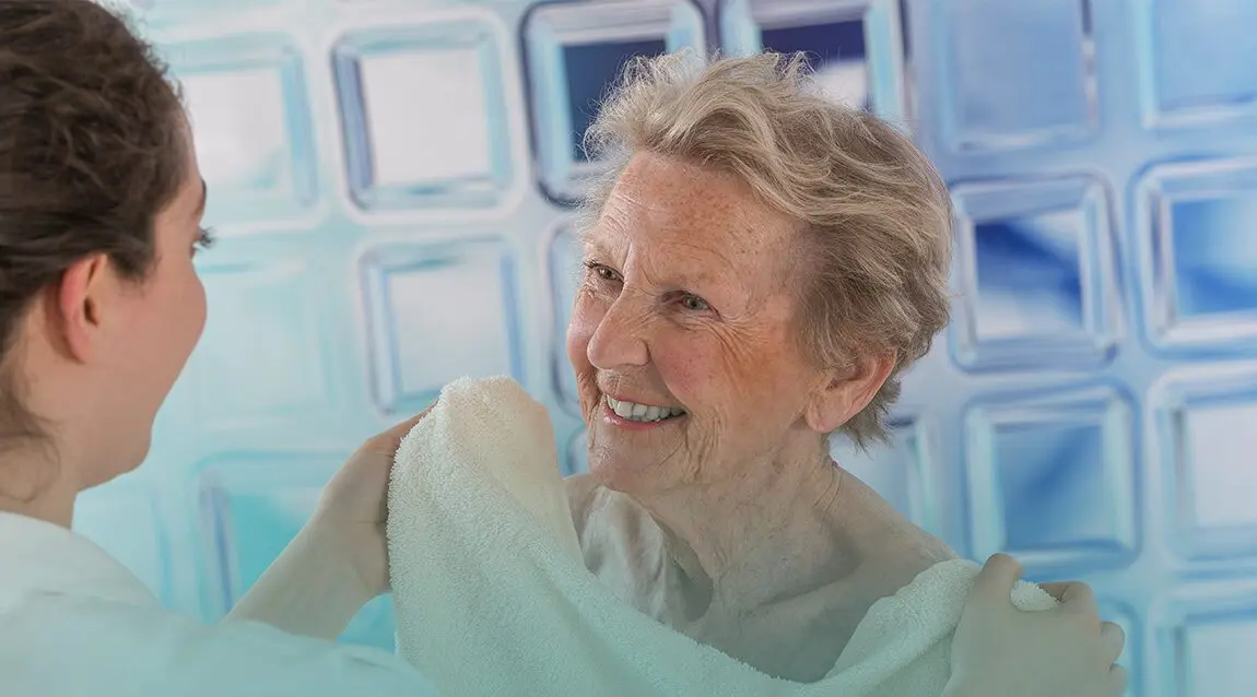 Cuidador ayudando a un adulto mayor a la hora del baño.