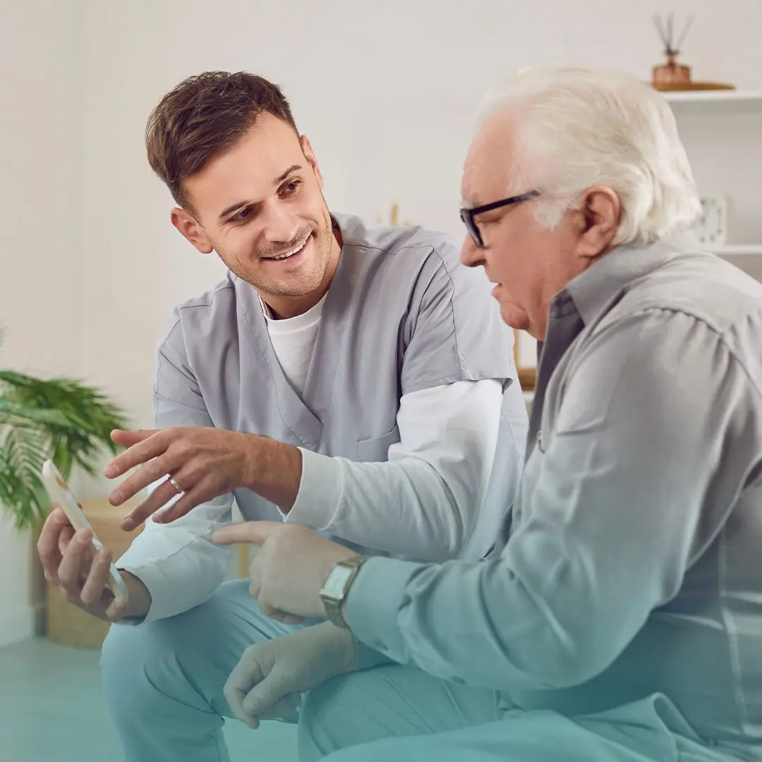 Cuidador se apoya en dispositivos tecnológicos para el cuidado del adulto mayor. 