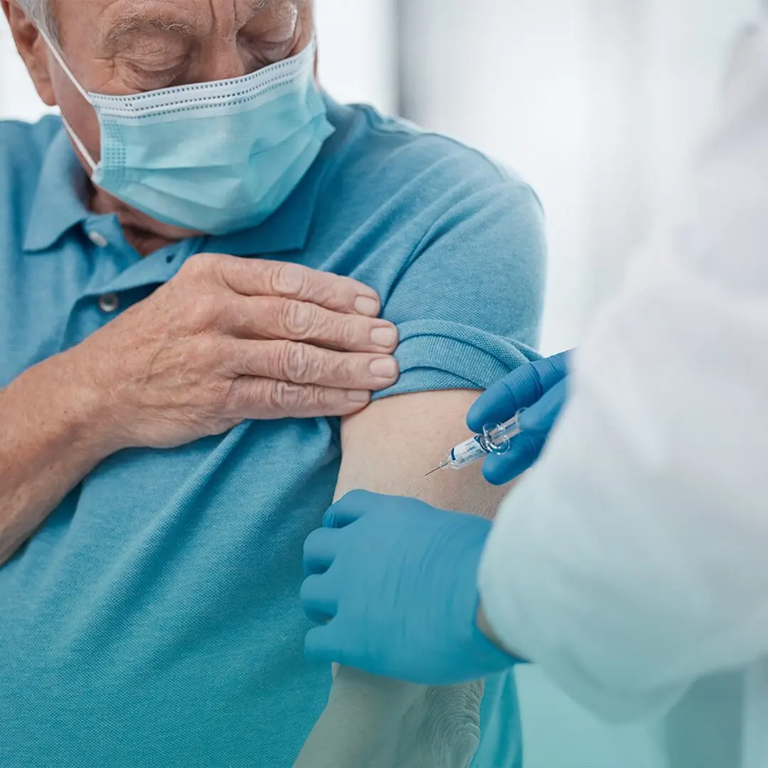 Adulto recibe sus vacunas con una inyección en el hombro.