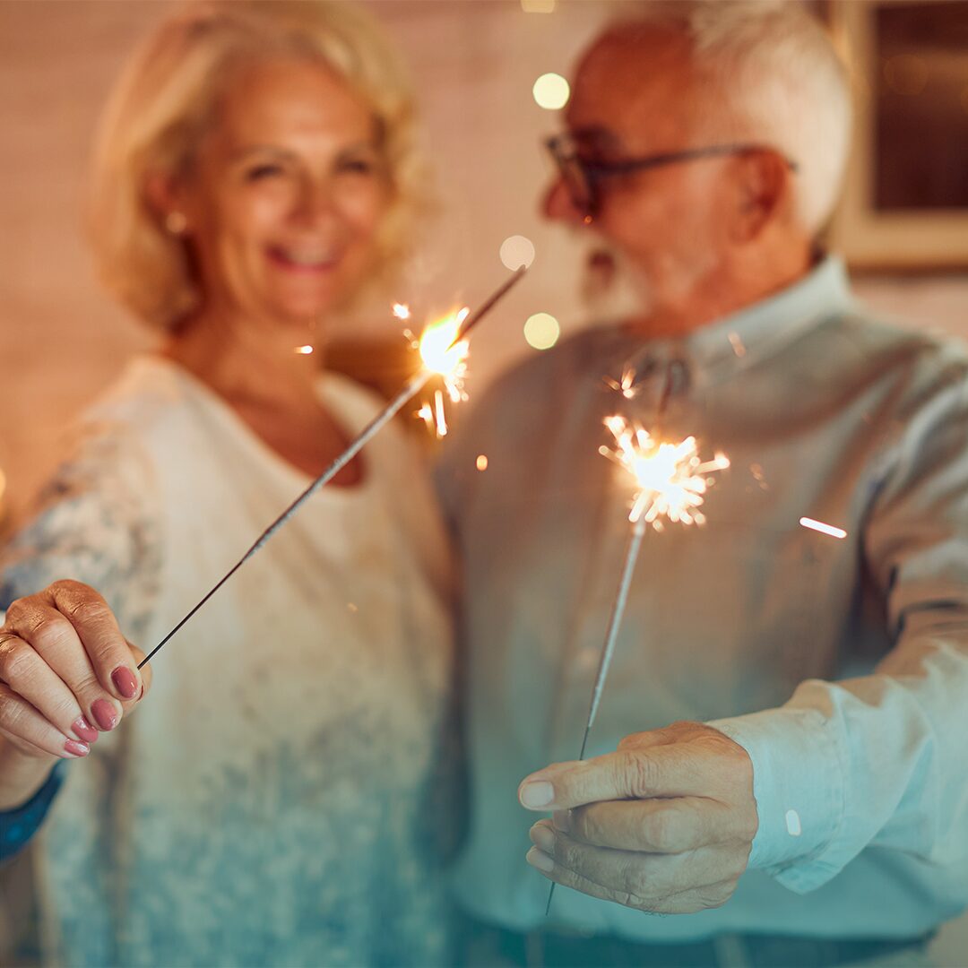 Adultos celebrando con luces la llegada de un año nuevo.